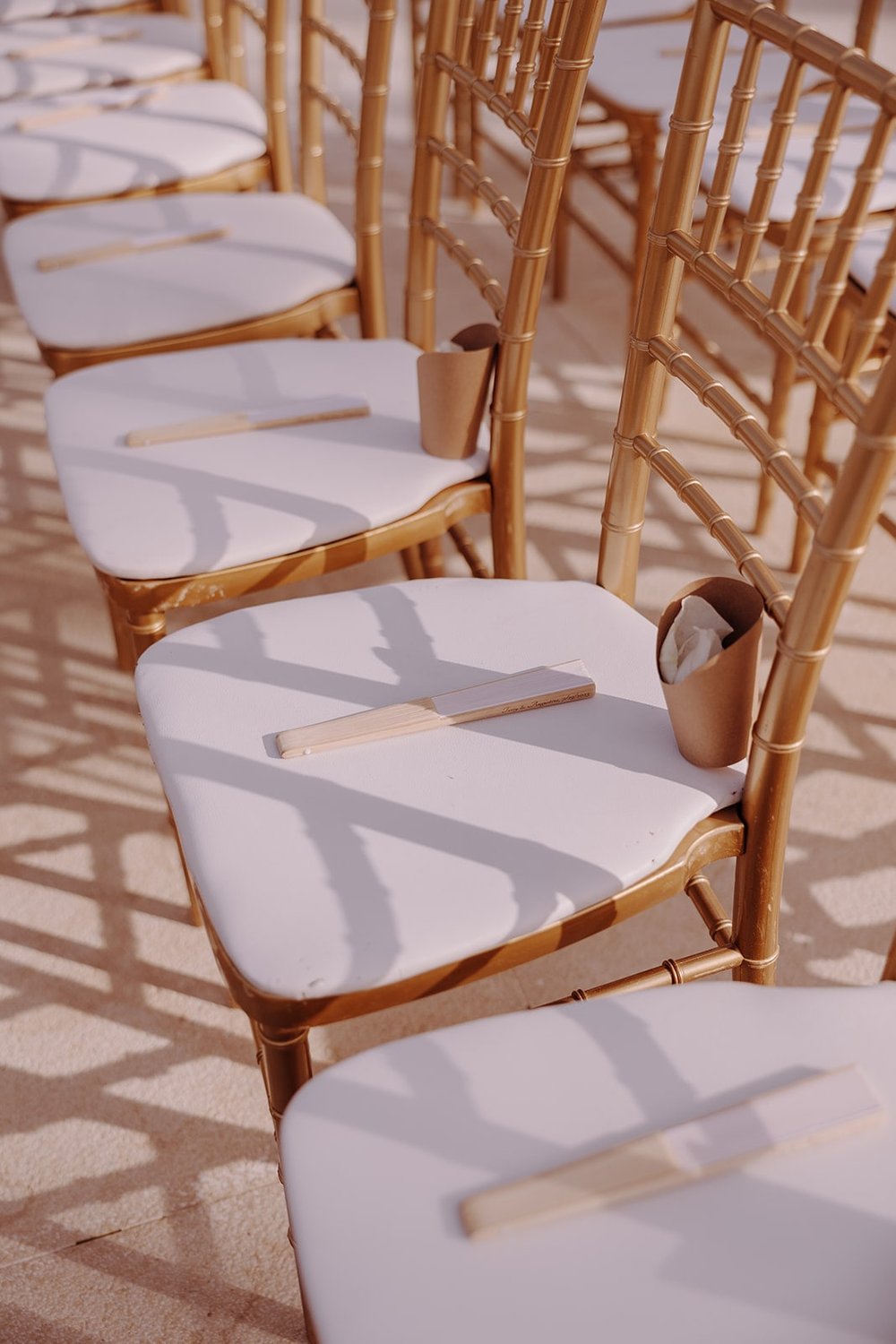 Custom fans sitting on wedding ceremony chairs at destination wedding