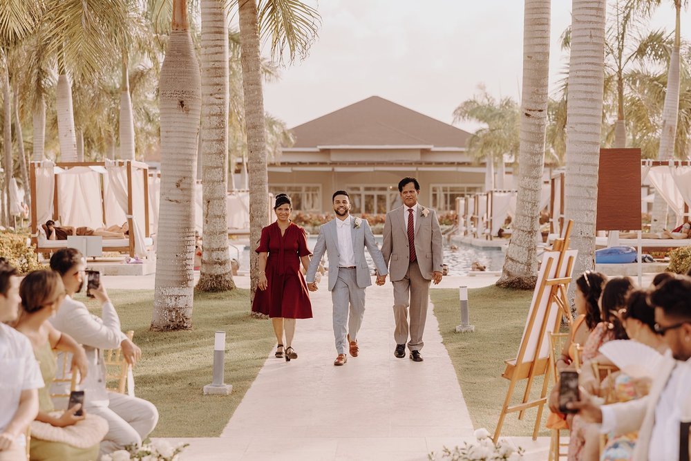 Groom enters destination wedding ceremony with his parents