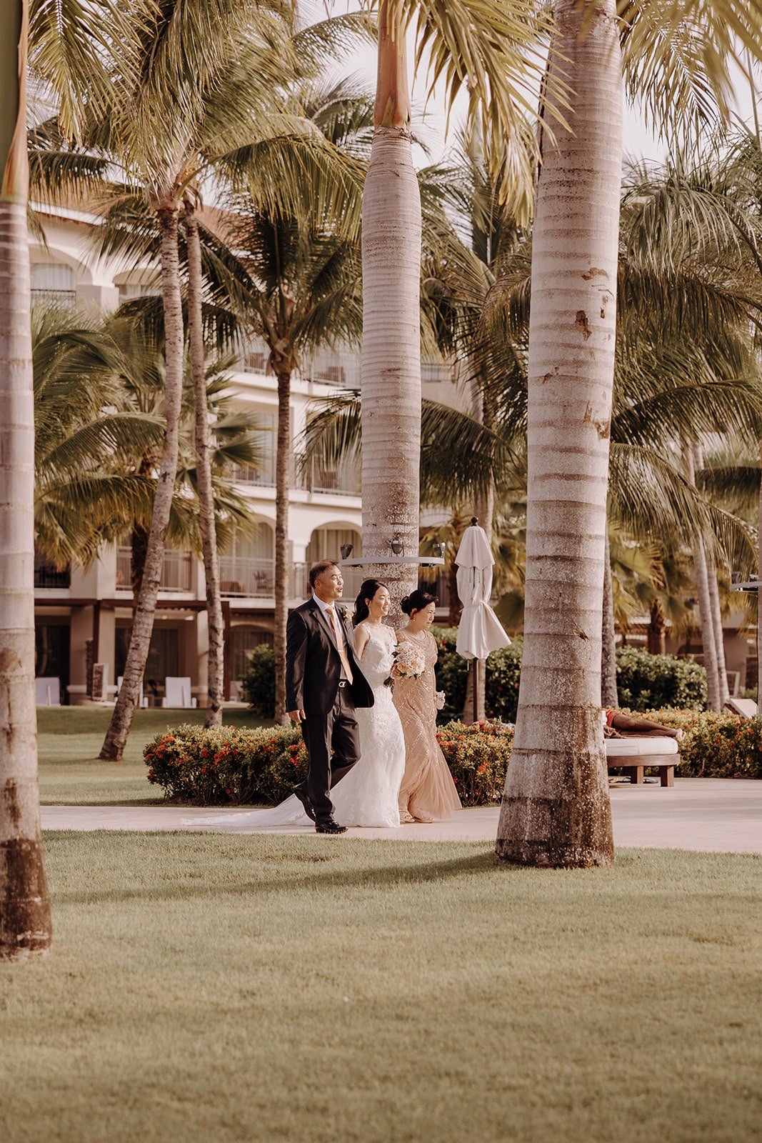 Bride enters Dreams Royal Beach Punta Cana wedding ceremony with her parents