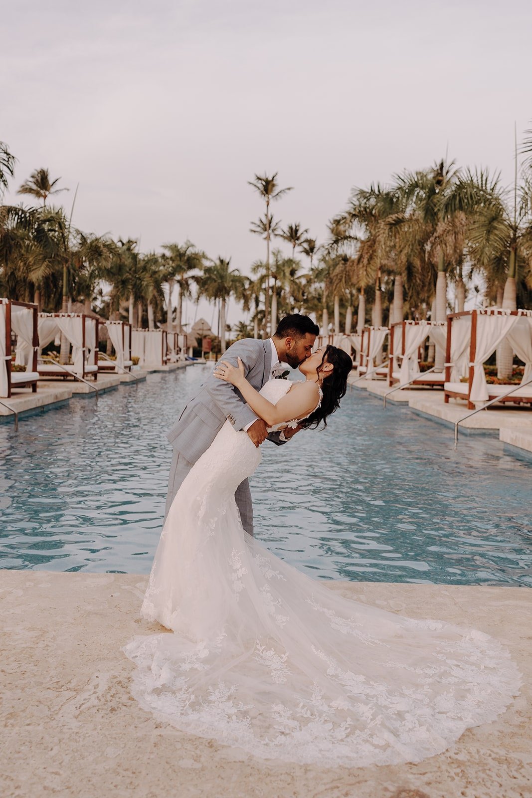 Groom dips bride for a kiss by the pool at their Dreams Royal Beach Punta Cana wedding