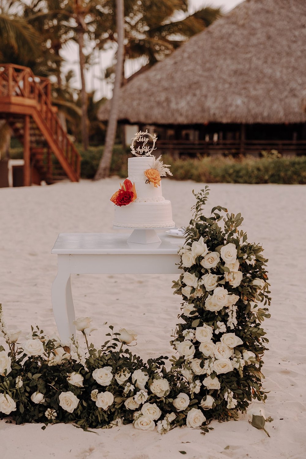 White two tier wedding cake with red and orange flowers