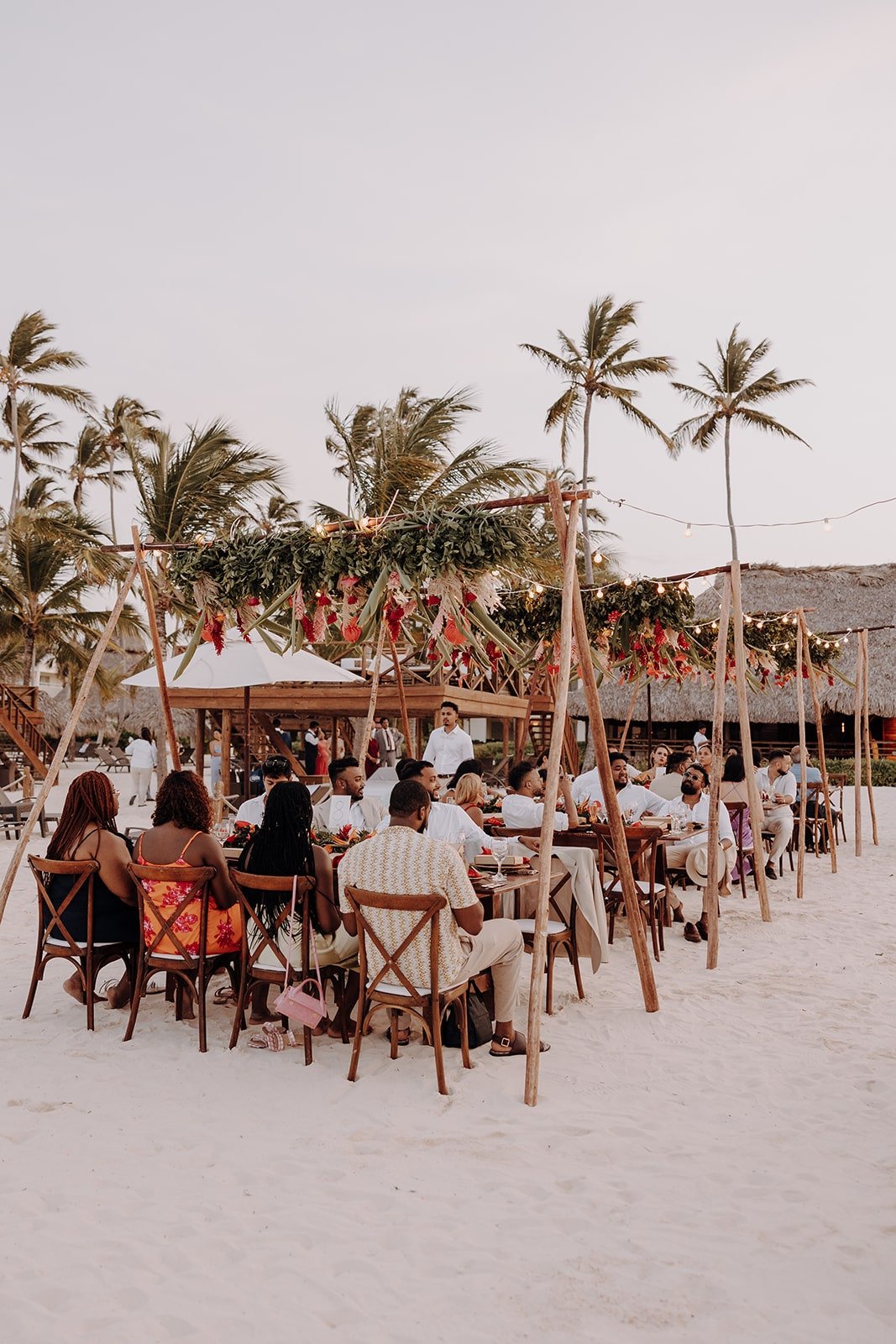 Guests sit at wedding reception tables on the beach at Dreams Royal Beach Punta Cana wedding