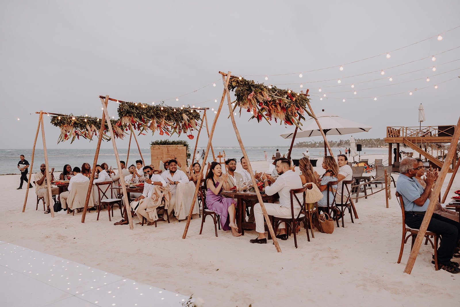 Guests sit at wedding reception tables on the beach at Dreams Royal Beach Punta Cana wedding