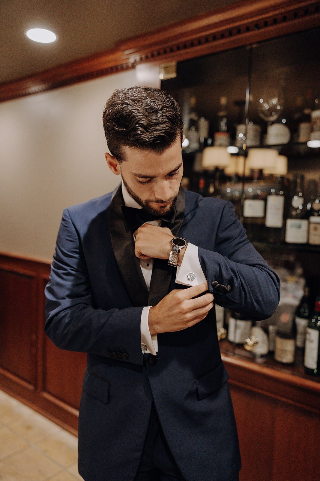 Groom adjusting cuff links while getting ready in the wine cellar at Kittle House wedding venue