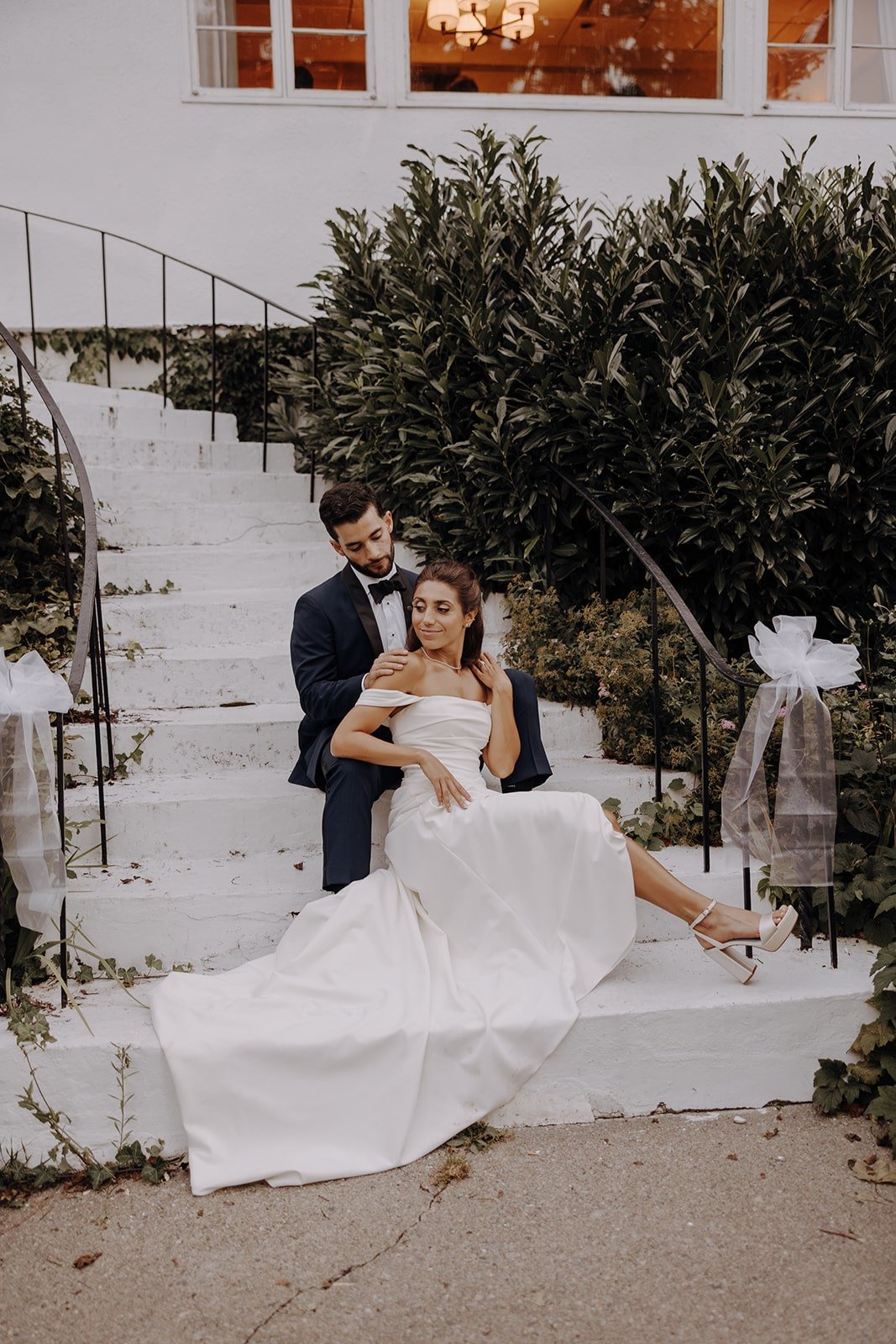 Bride and groom sit on the steps at Crabtree's Kittle House wedding venue during sunset photos