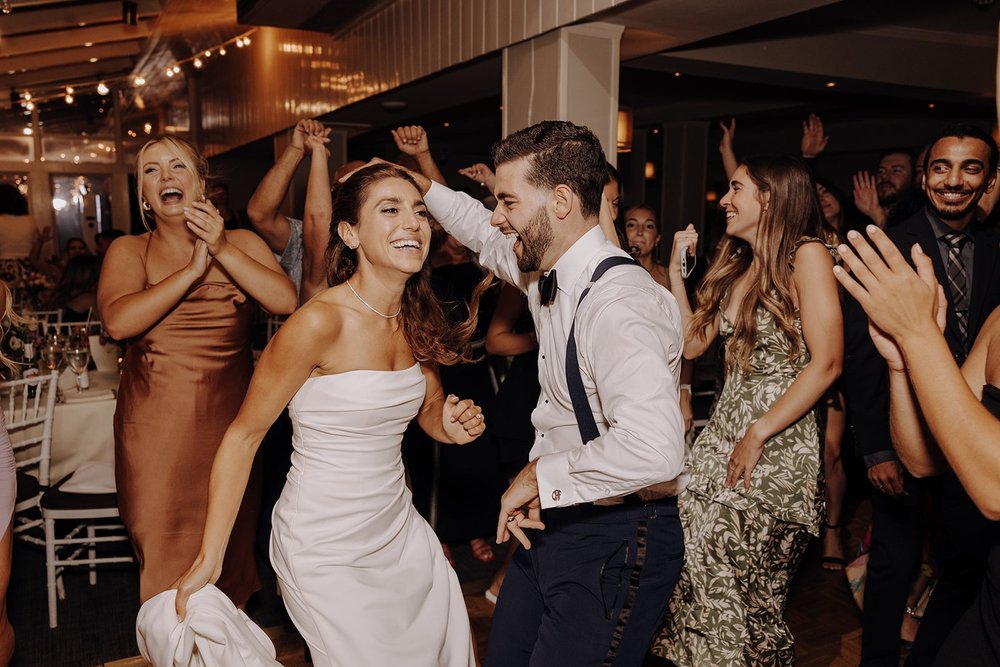 Bride and groom dance with guests on the dance floor at New York wedding reception