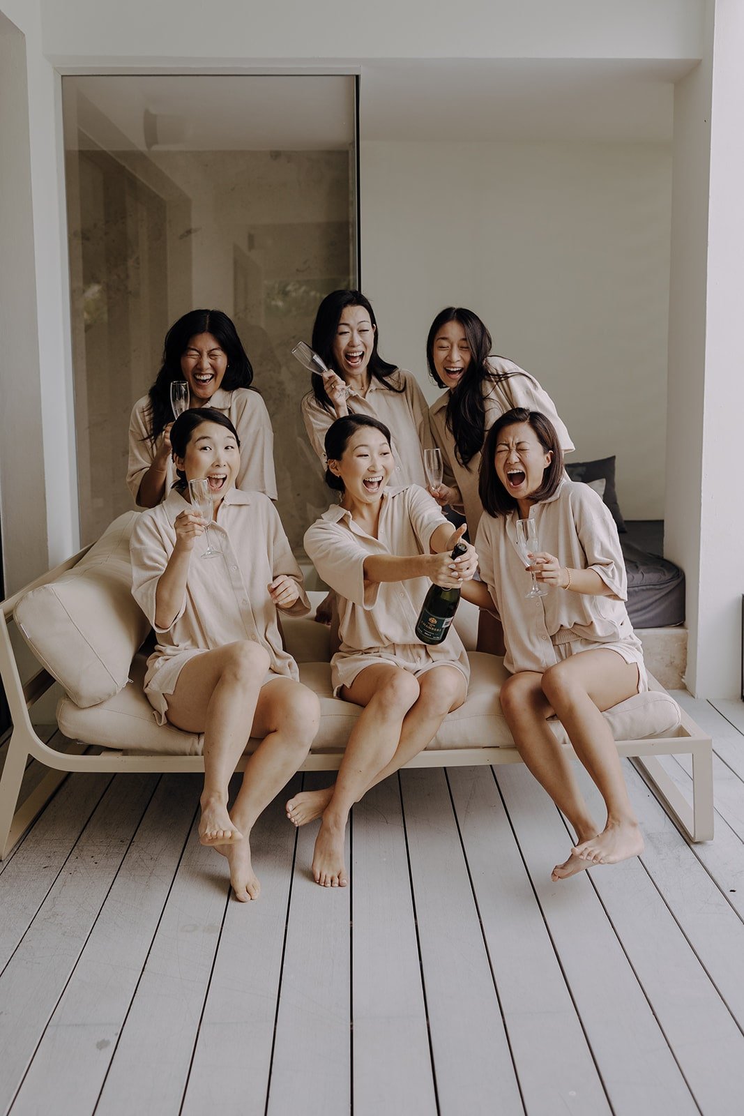 Bride and bridesmaids pop champagne while getting ready for a resort wedding in Mexico