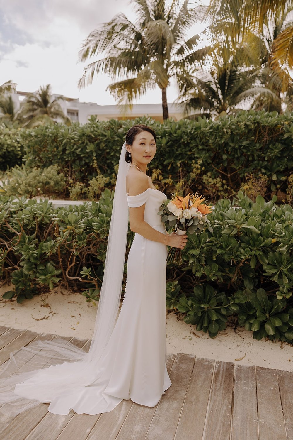 Bride holding orange floral bouquet during her resort wedding in Mexico