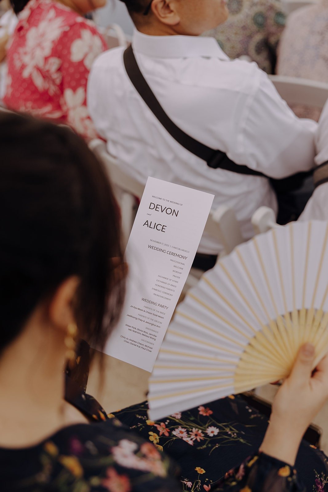 Wedding guest fanning herself while reading the Mexico resort wedding schedule