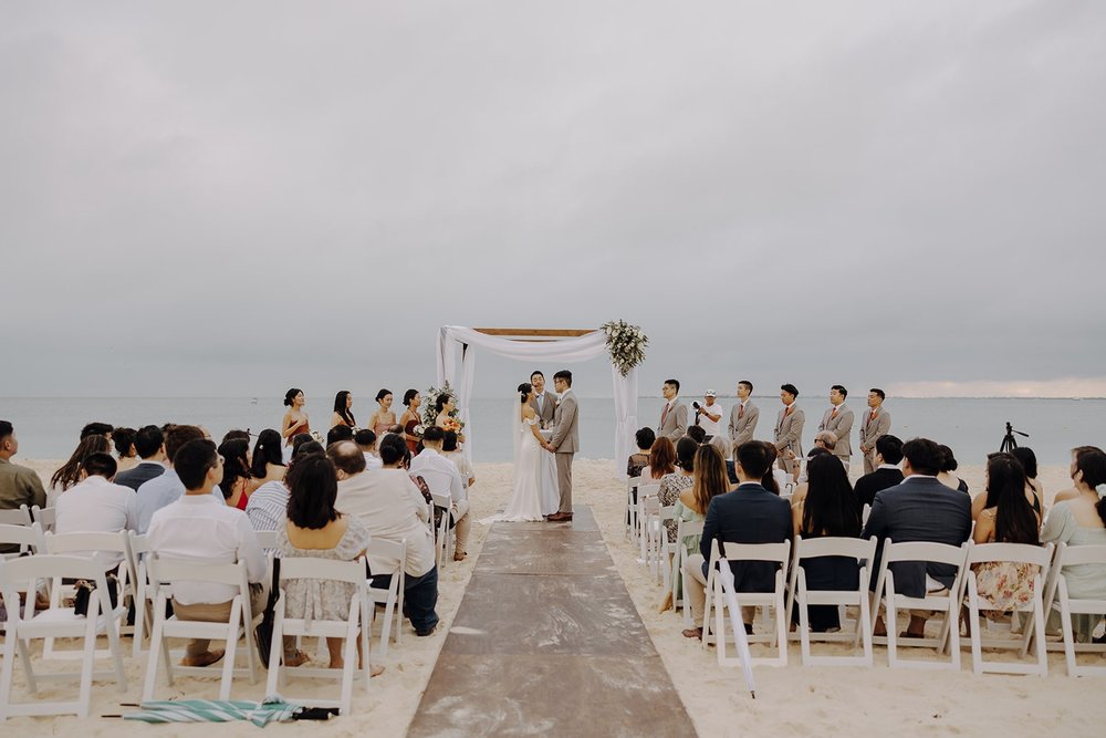 Bride and groom hold hands during their Mexico resort wedding ceremony on the beach