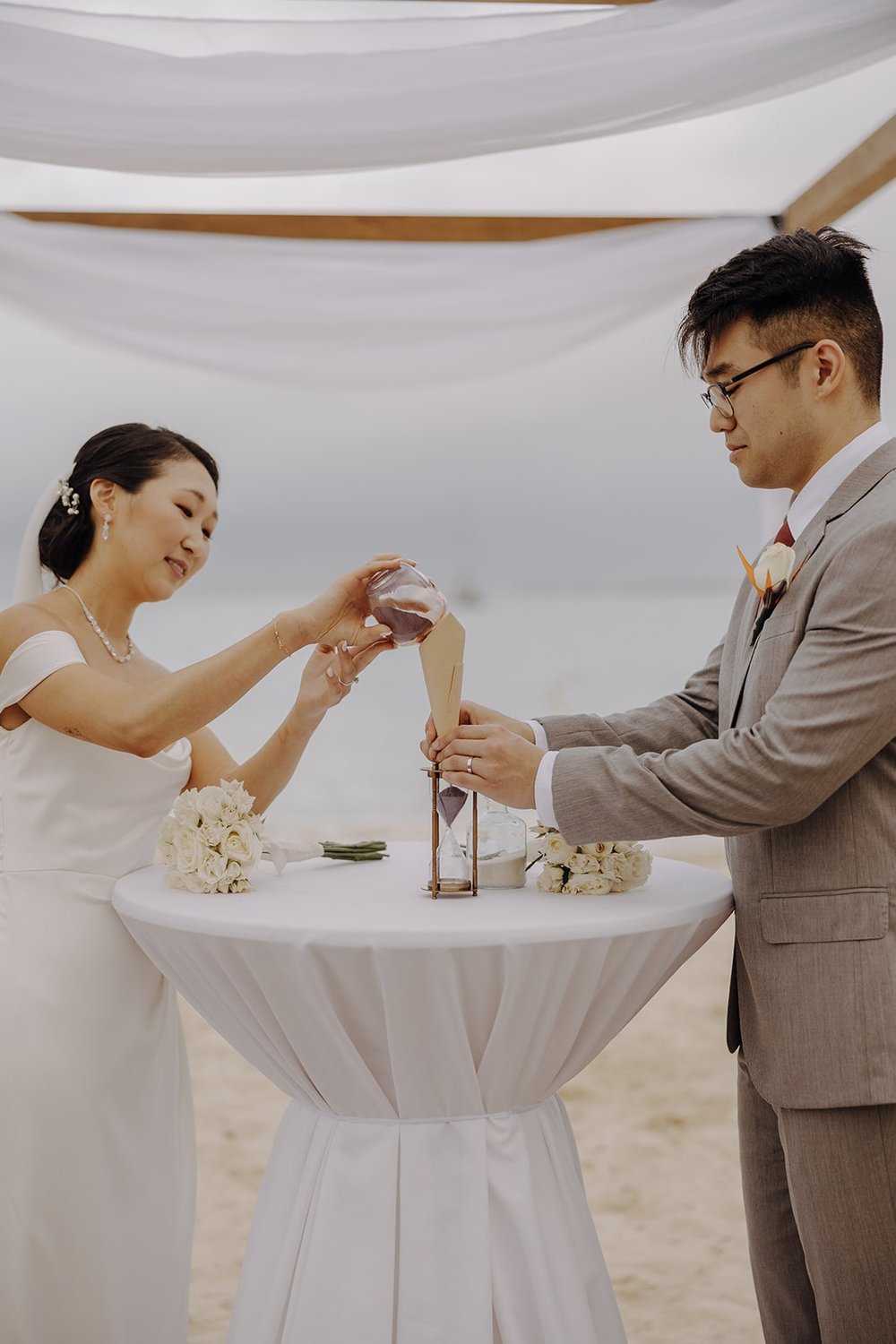 Bride and groom pour sand during their Mexico resort wedding ceremony on the beach