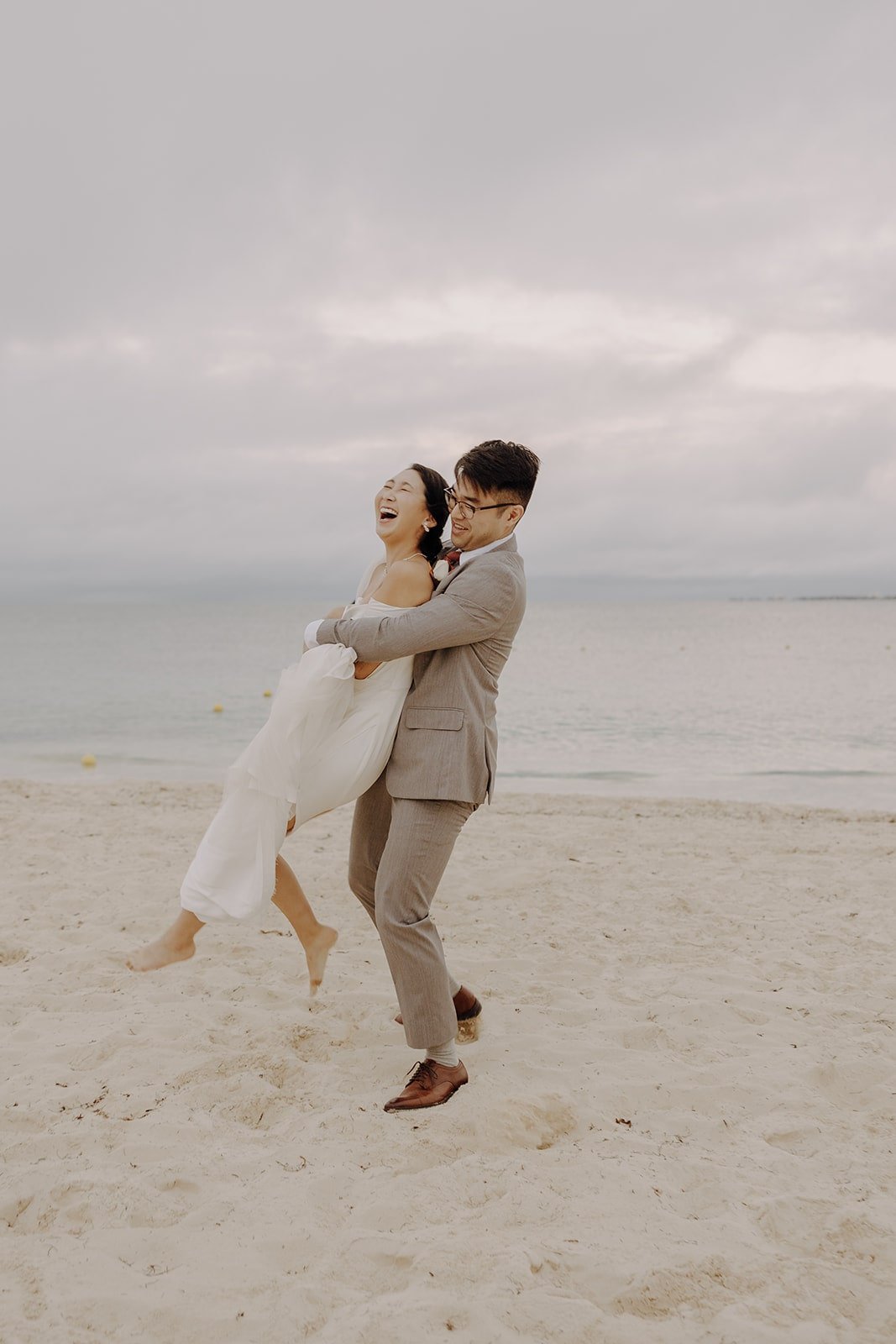 Bride and groom run around the beach during their resort wedding in Mexico