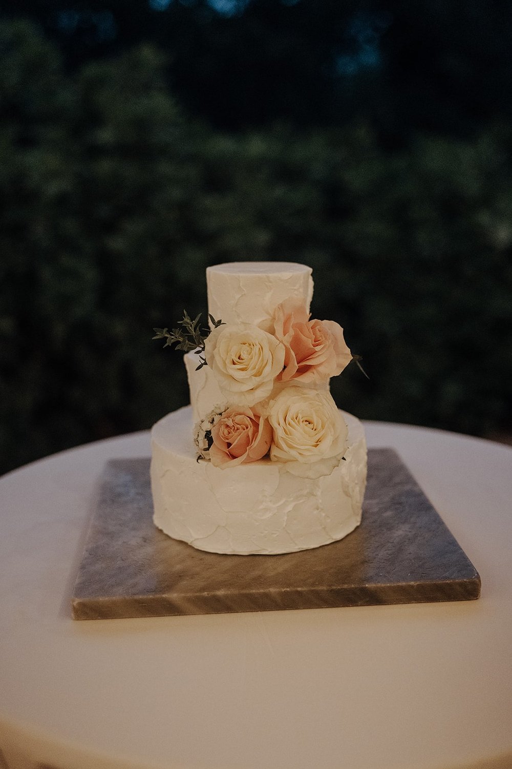 Three tier white wedding cake with orange and pink flowers