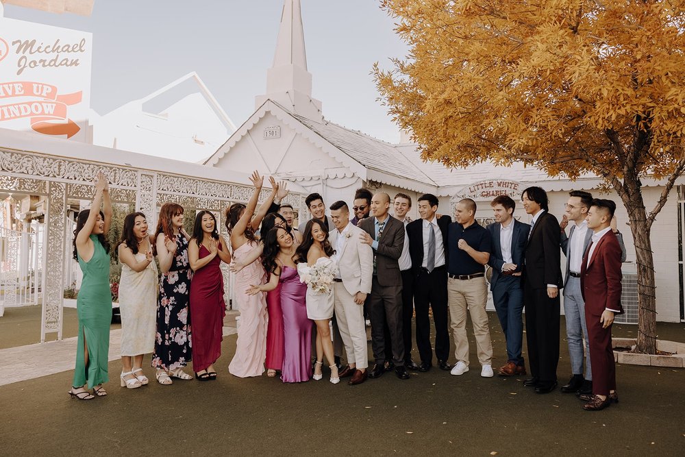 Guests cheer with bride and groom at their Las Vegas elopement at the Little White Chapel