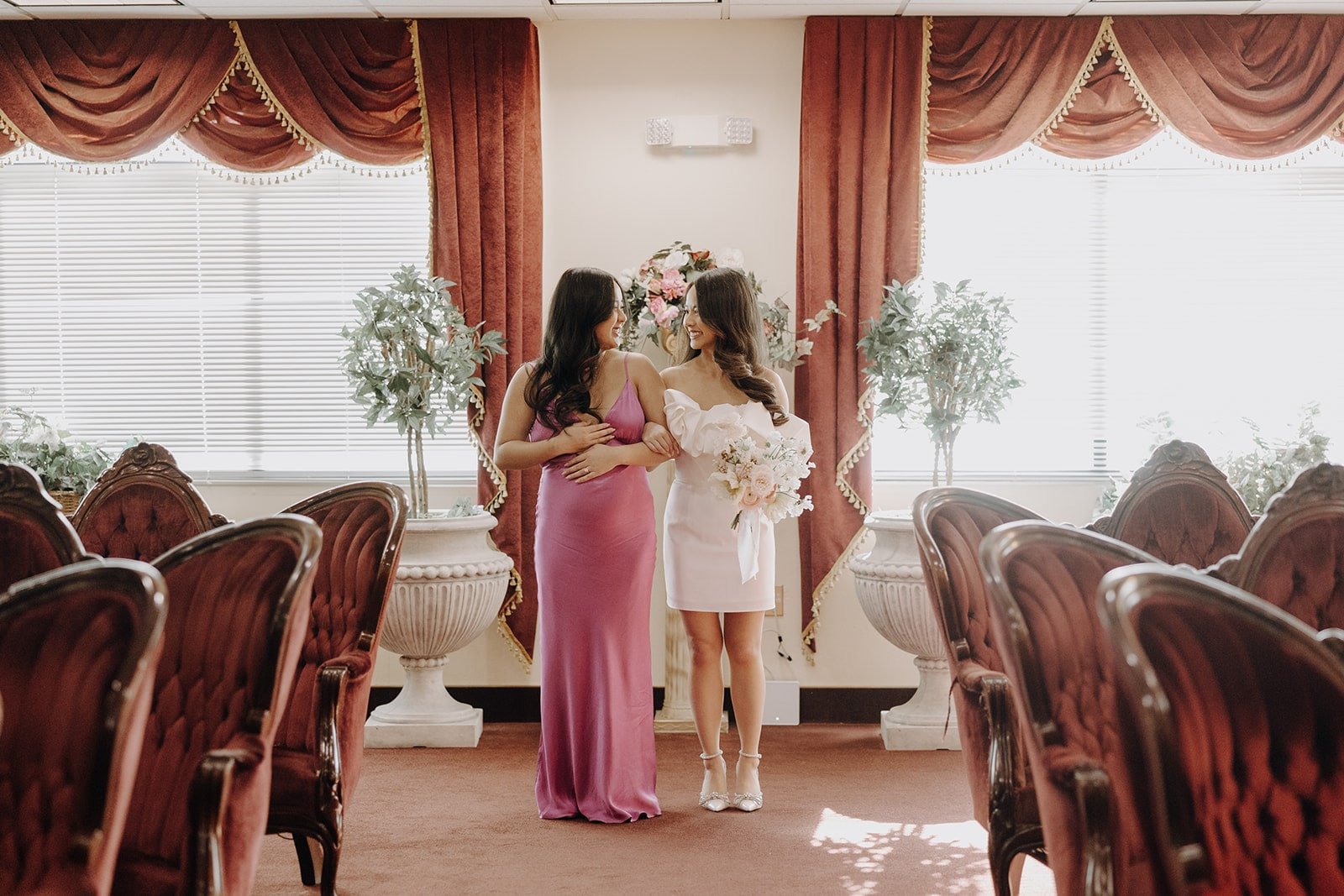 Bride walks down the aisle with her friend at a Las Vegas elopement at the Little White Chapel