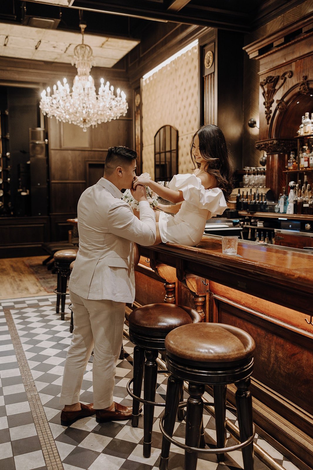 Groom kisses brides hand while she sits on the bar at a speakeasy in Las Vegas