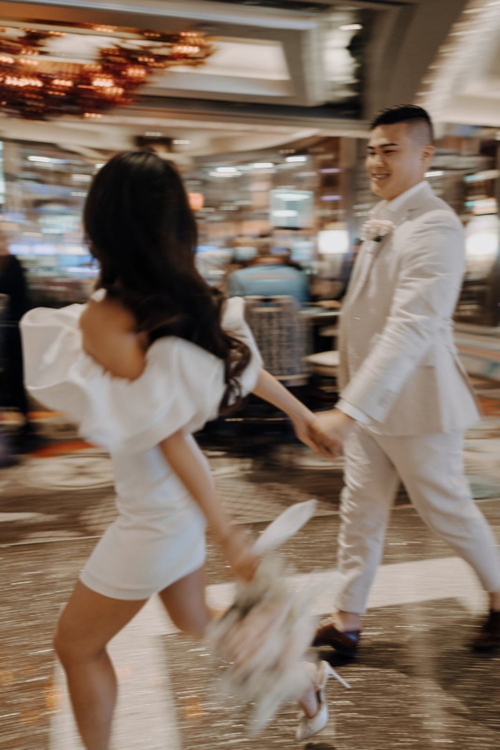 Bride and groom run through the halls of a hotel during their Las Vegas elopement