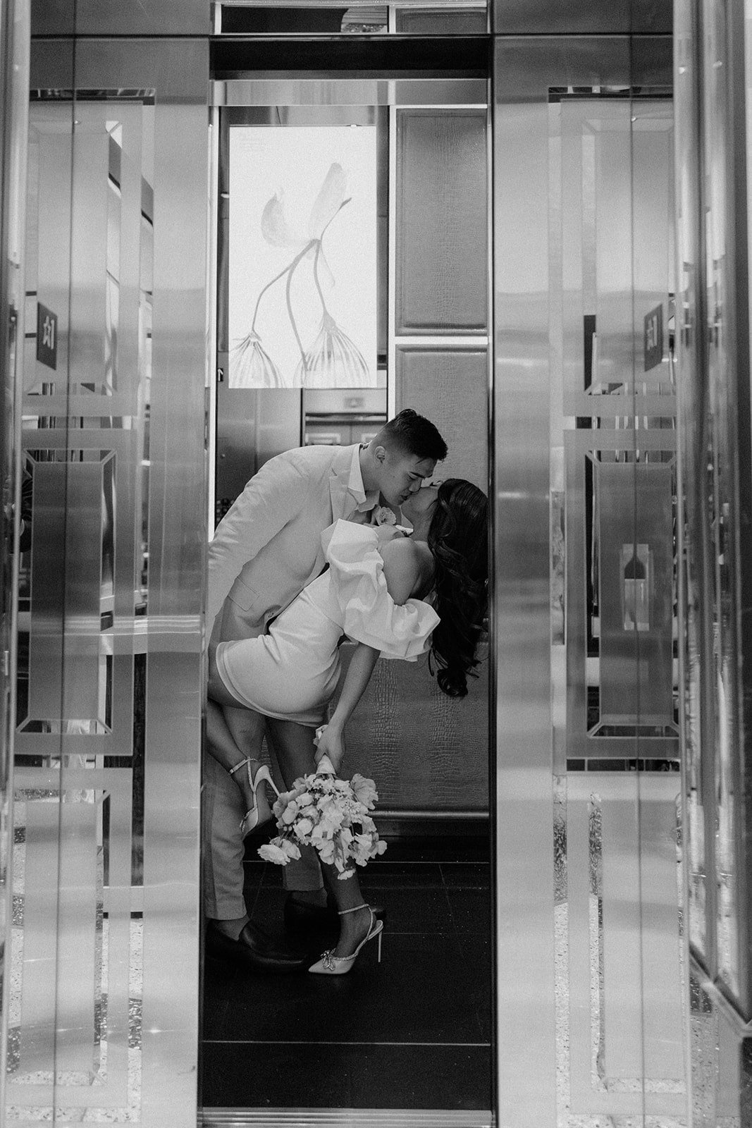 Groom dips bride for a kiss in their hotel elevator at their Las Vegas elopement
