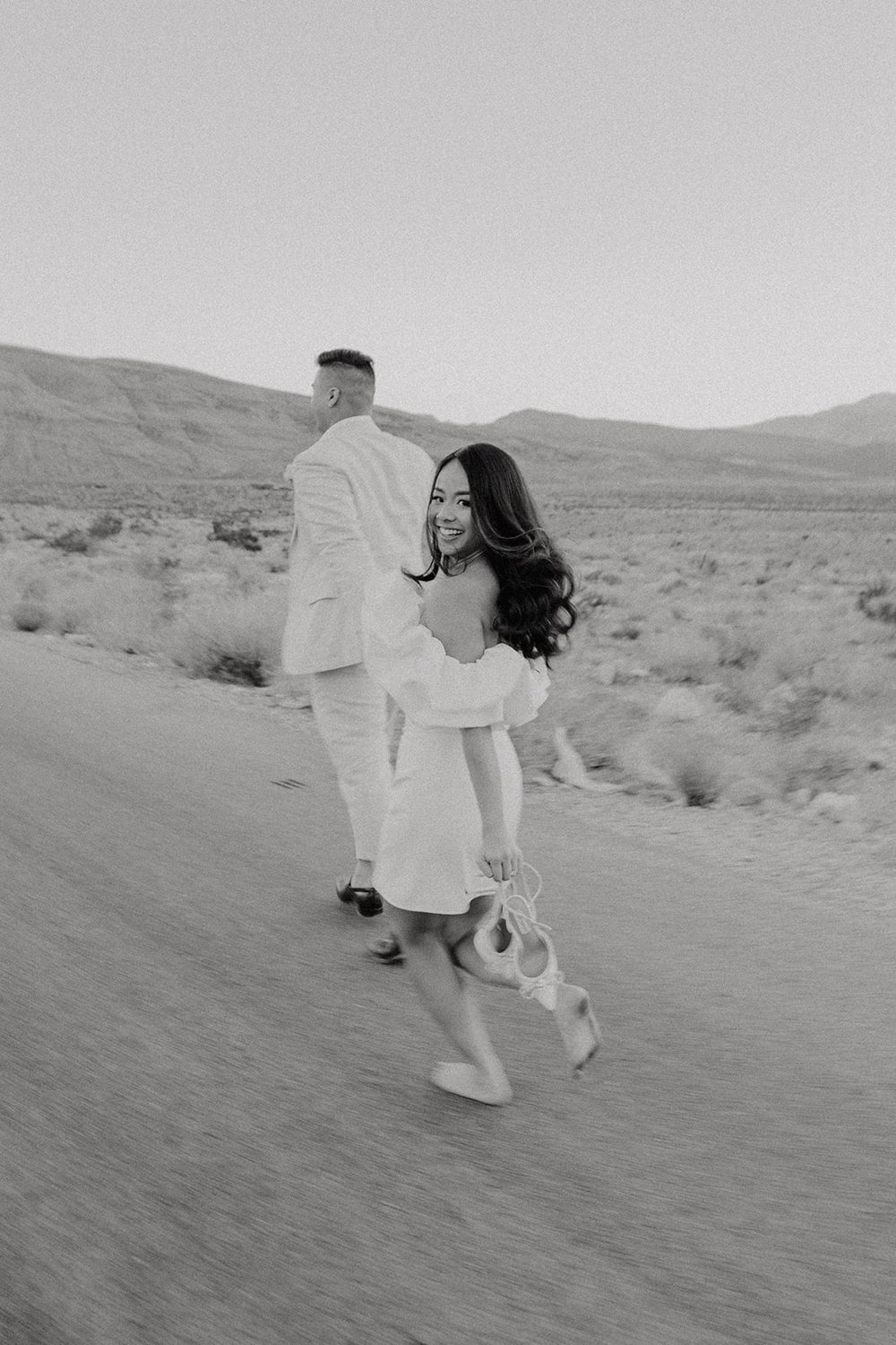 Bride and groom hold hands and run through the street at their Las Vegas elopement in Red Rock Canyon