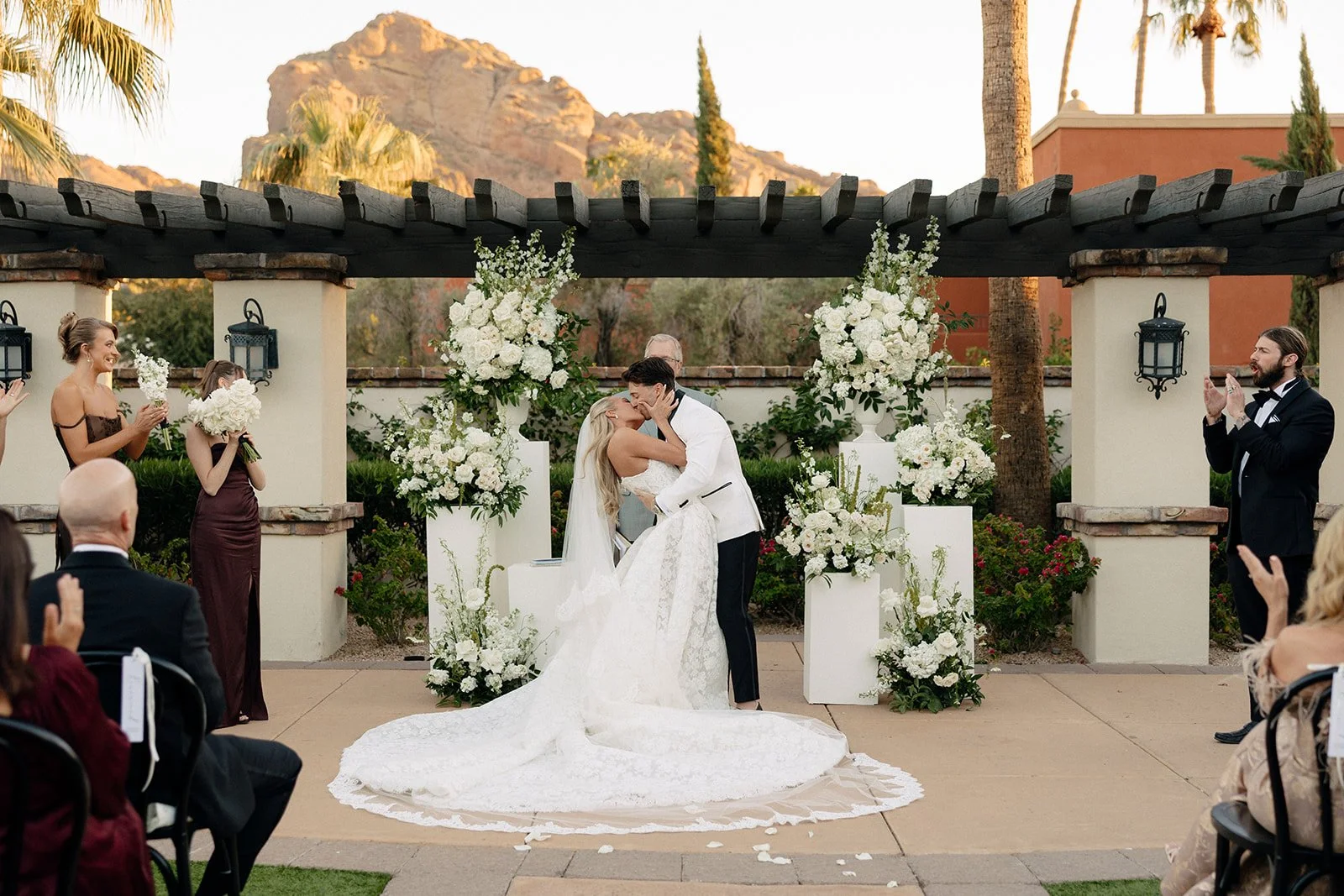 Outdoor wedding ceremony with seated guests, floral arrangements, and mountain scenery in the background under a clear sky for a luxury wedding