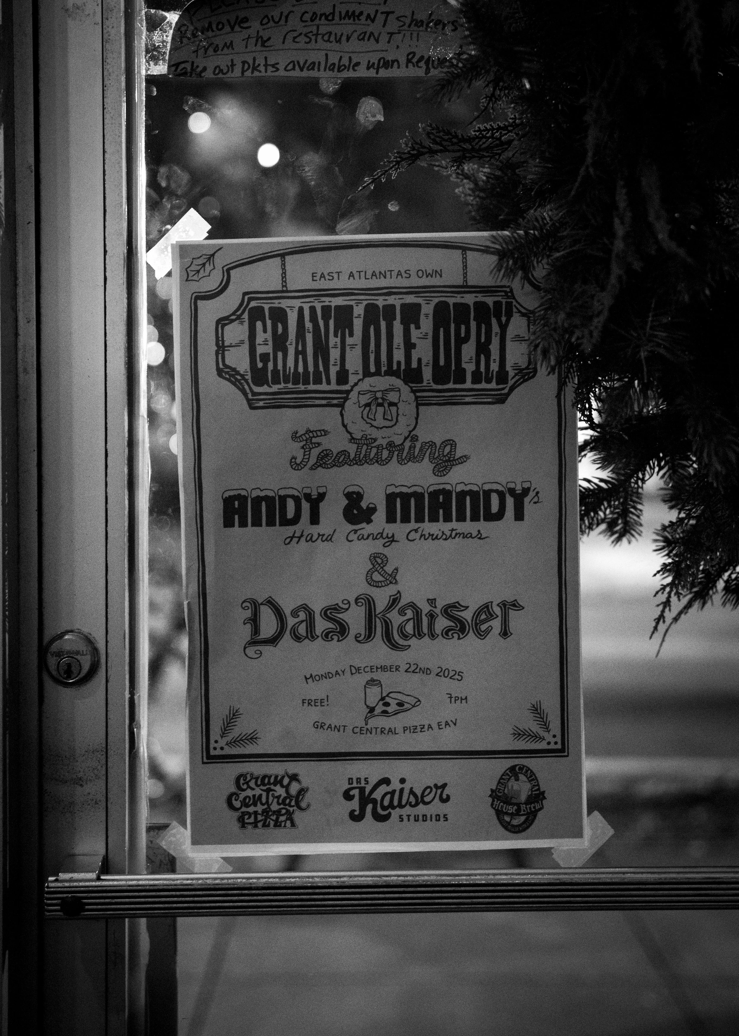 Poster in a window advertising a holiday event featuring Andy & Mandy and Daskaiser, with details of date, time, and location.