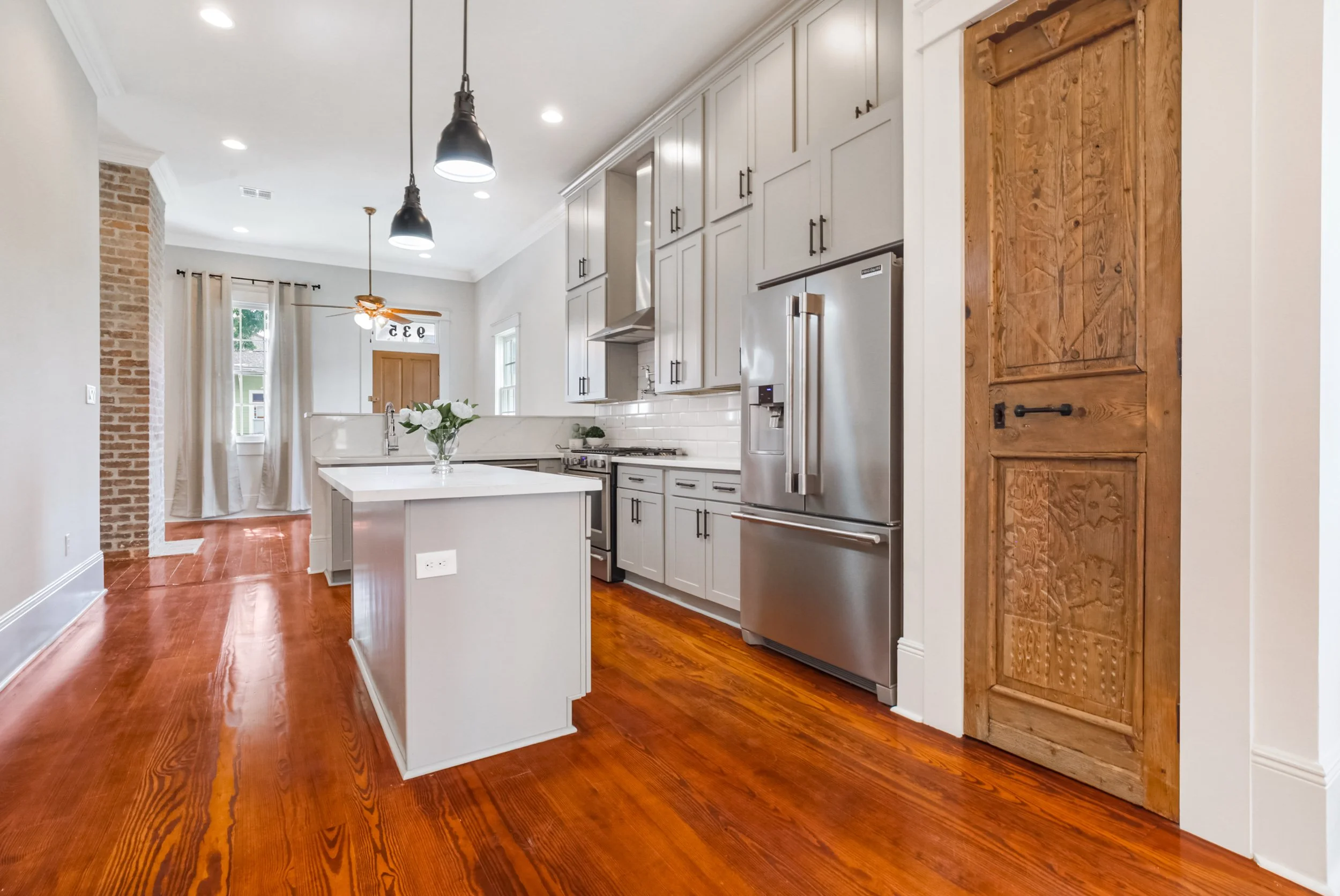 Completed kitchen remodel featuring gray cabinetry, quartz island, stainless steel appliances, and hardwood flooring