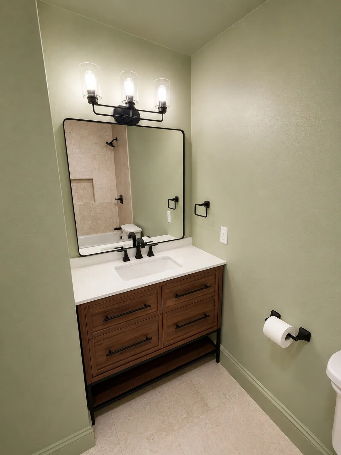 This custom bathroom renovation in New Orleans, Louisiana, features a modern wood vanity with quartz countertops, a rectangular undermount sink, matte black plumbing fixtures, a framed vanity mirror, and updated designer lighting. Grand Rising Constr
