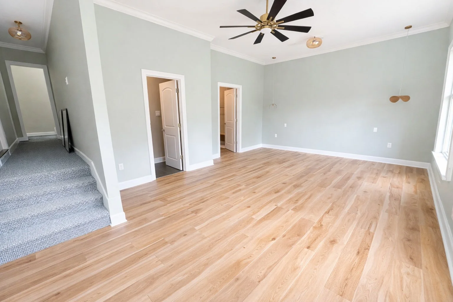 Wide-angle view of engineered wood flooring installed in an open-concept living space with natural light, clean finishes, and professional craftsmanship in Covington, LA by Grand Rising Construction.