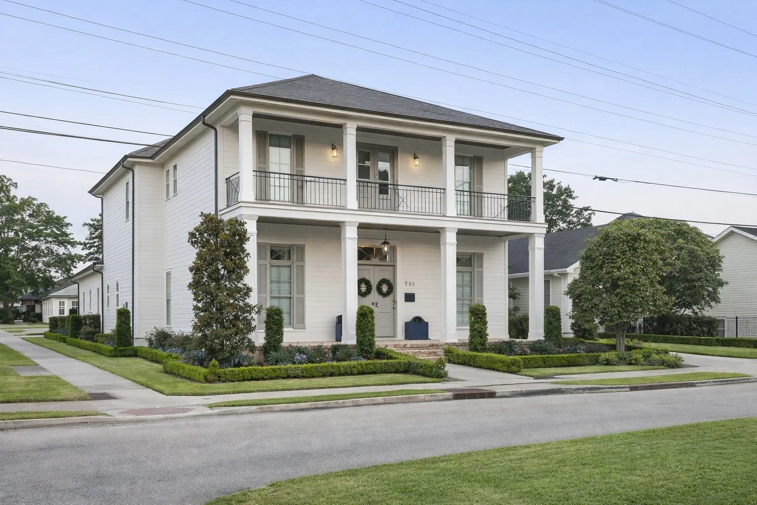 New construction two-story home in Covington, Louisiana featuring a columned porch, balcony, and professionally landscaped exterior.
