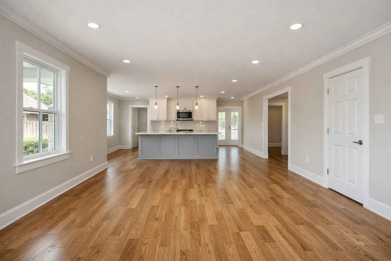 Wide-angle interior photo of a fully renovated open-concept living space in a Southern Louisiana home, featuring new hardwood floors, fresh neutral paint, modern trim, and upgraded lighting.