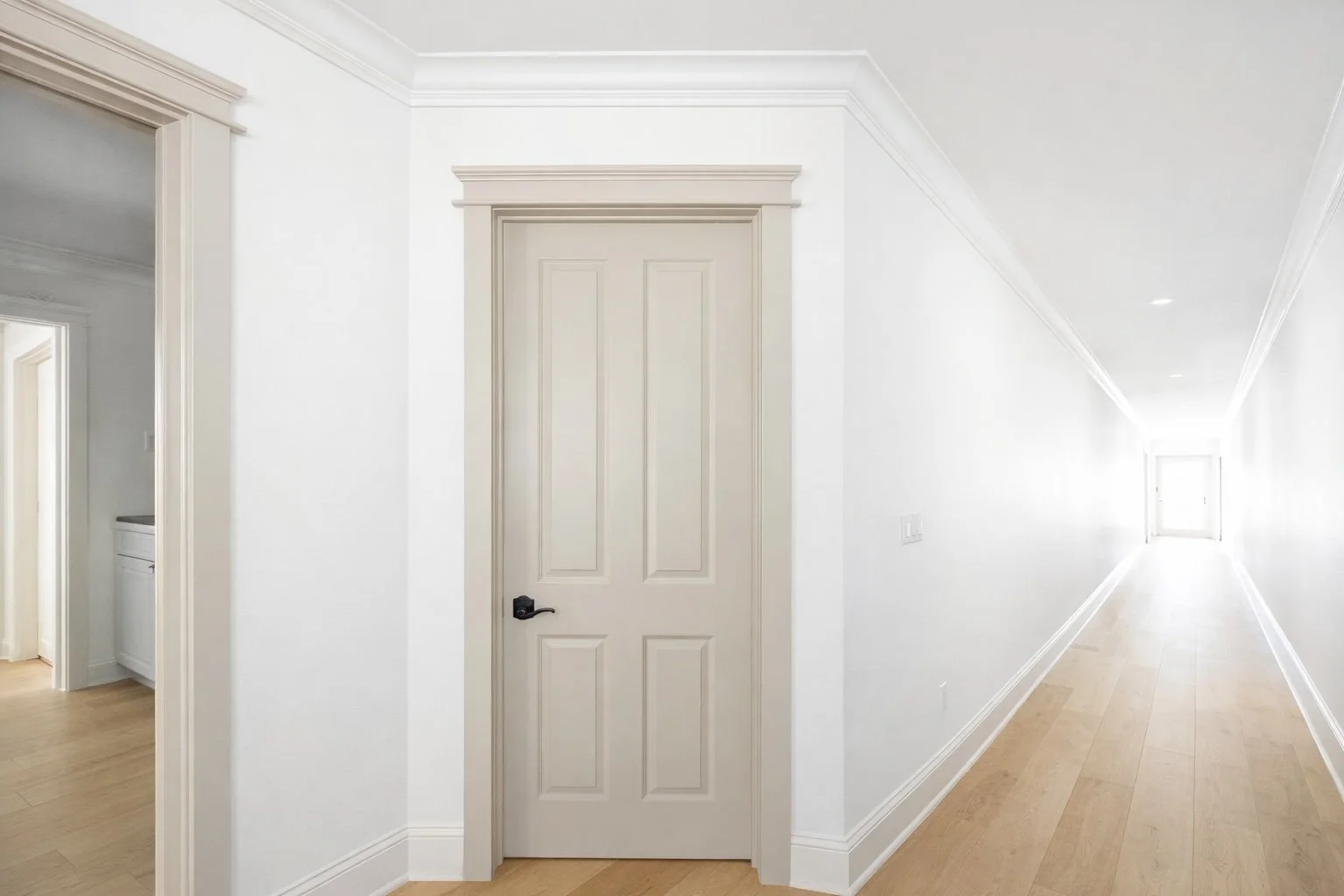 High-end trim carpentry featuring 8-foot wood door, custom casing, baseboards, and crown molding.