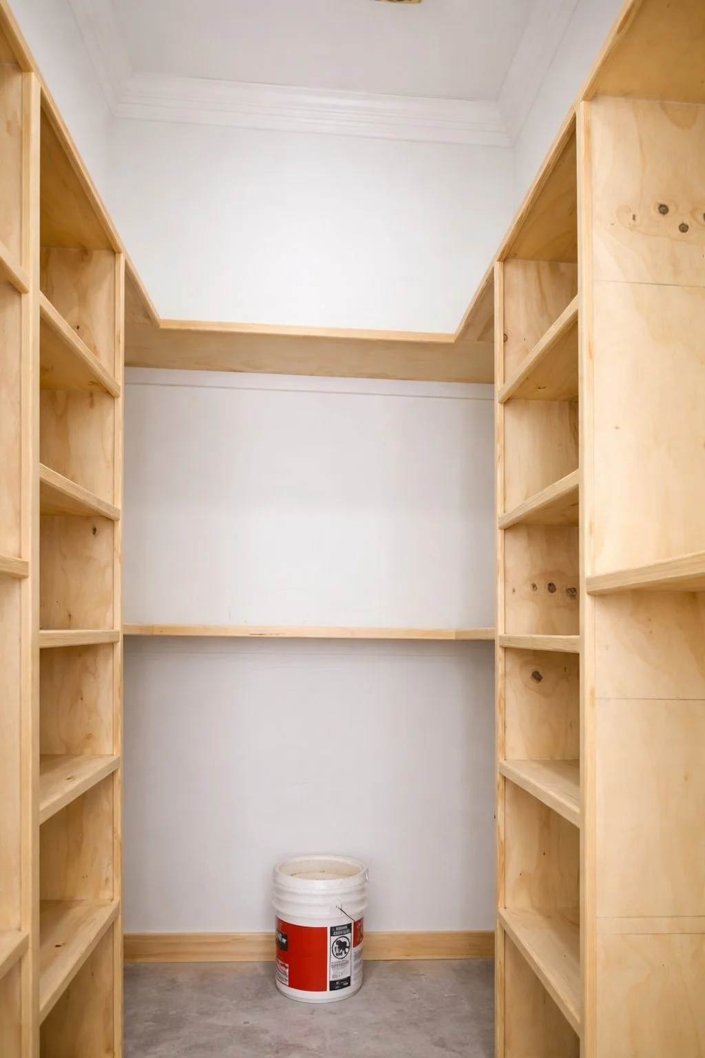Custom trim carpentry walk-in closet shelving with built-in plywood shelves and clean crown molding in Covington, Louisiana.