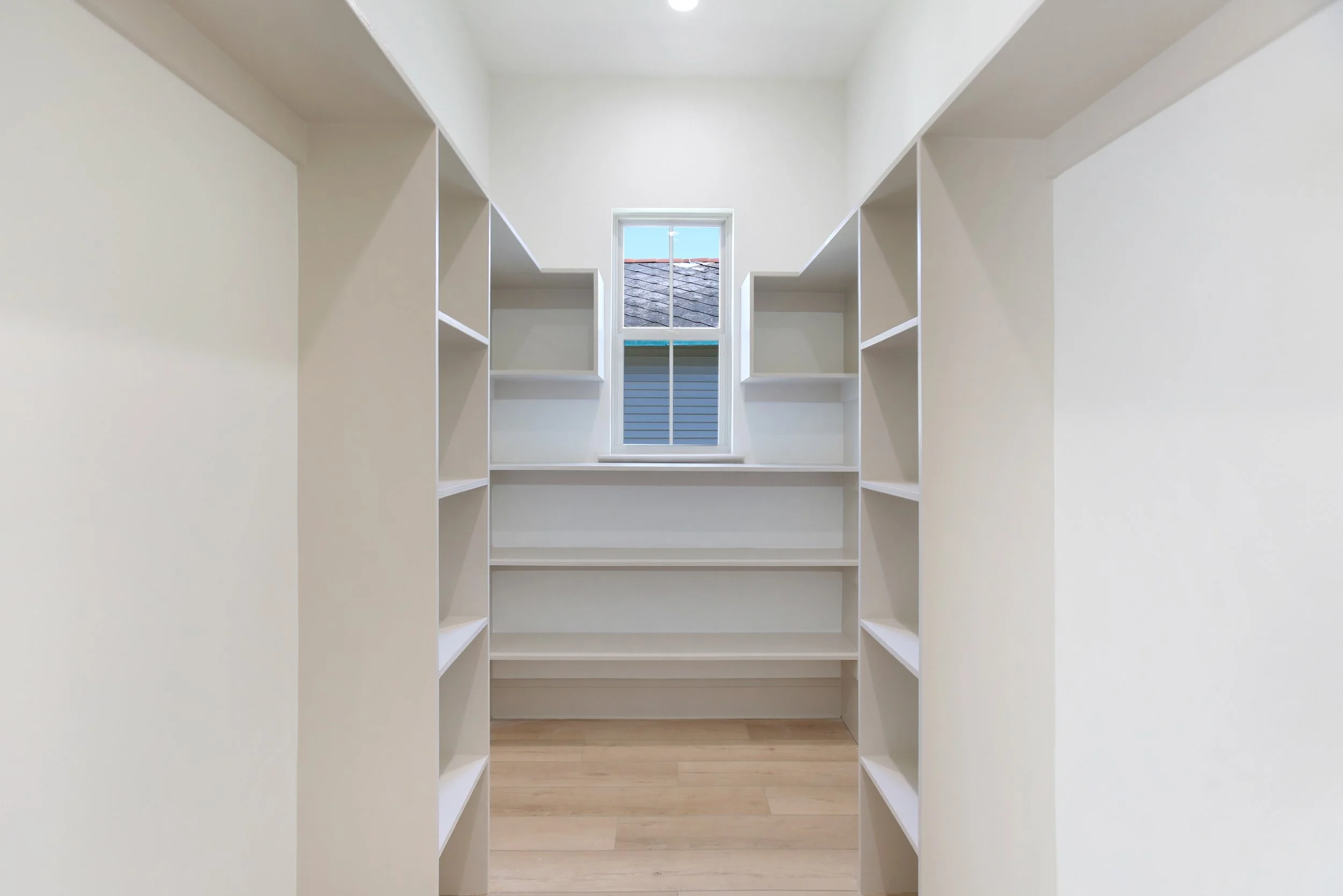 Precision trim carpentry in a custom walk-in closet featuring floor-to-ceiling built-in shelving and balanced layout by Grand Rising Costruction.