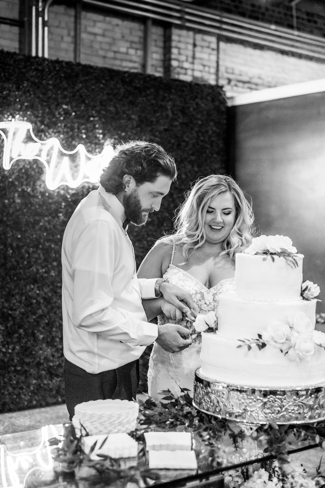 A bride and groom cutting their wedding cake together at a celebration at Studio 215 a modern warehouse venue in Fayetteville, NC