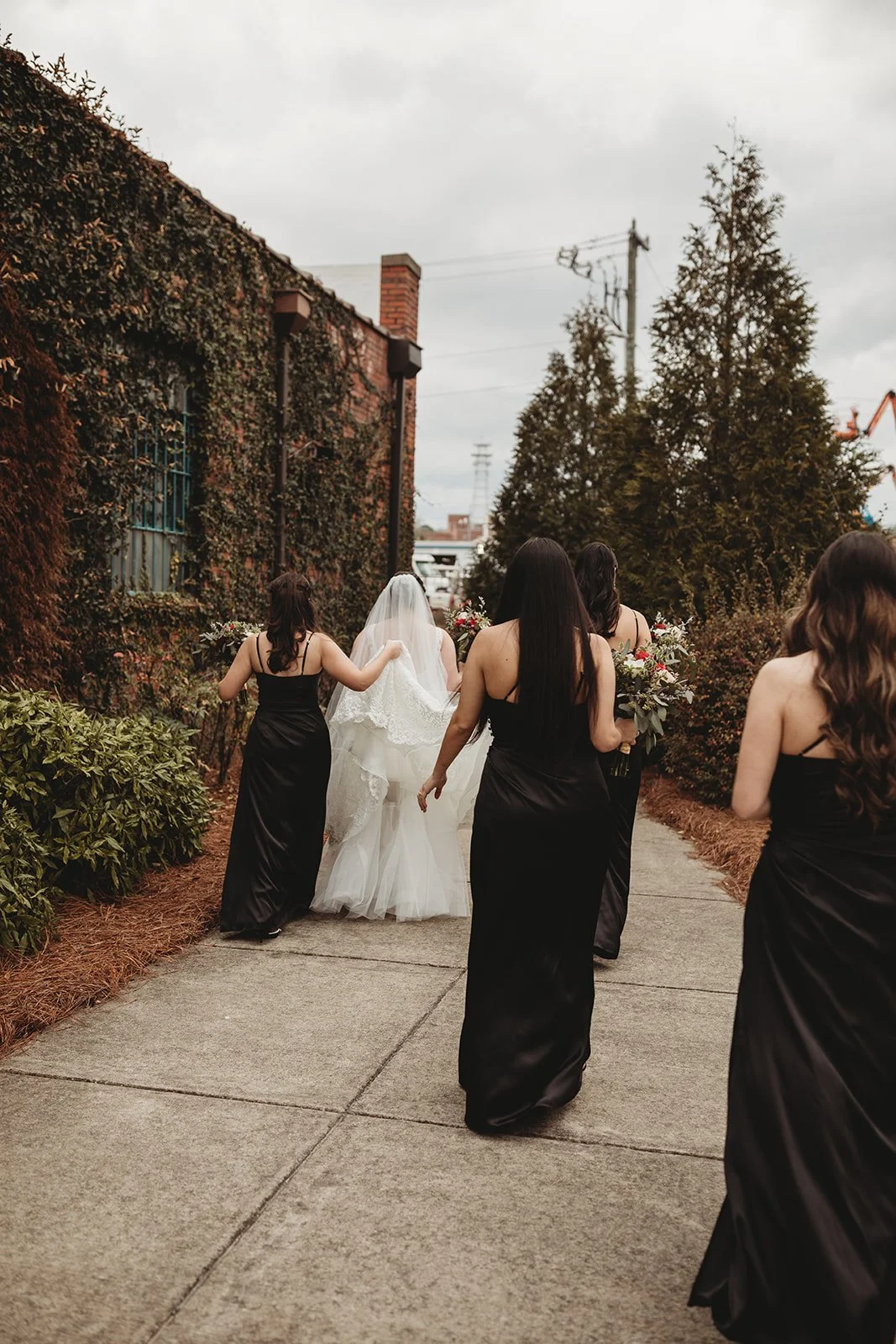 Bride and groom posing in front of the signature green ivy wall at Studio 215 in downtown Fayetteville, NC; a lush urban garden photography backdrop at our industrial warehouse venue near Fort Bragg and Raleigh.
