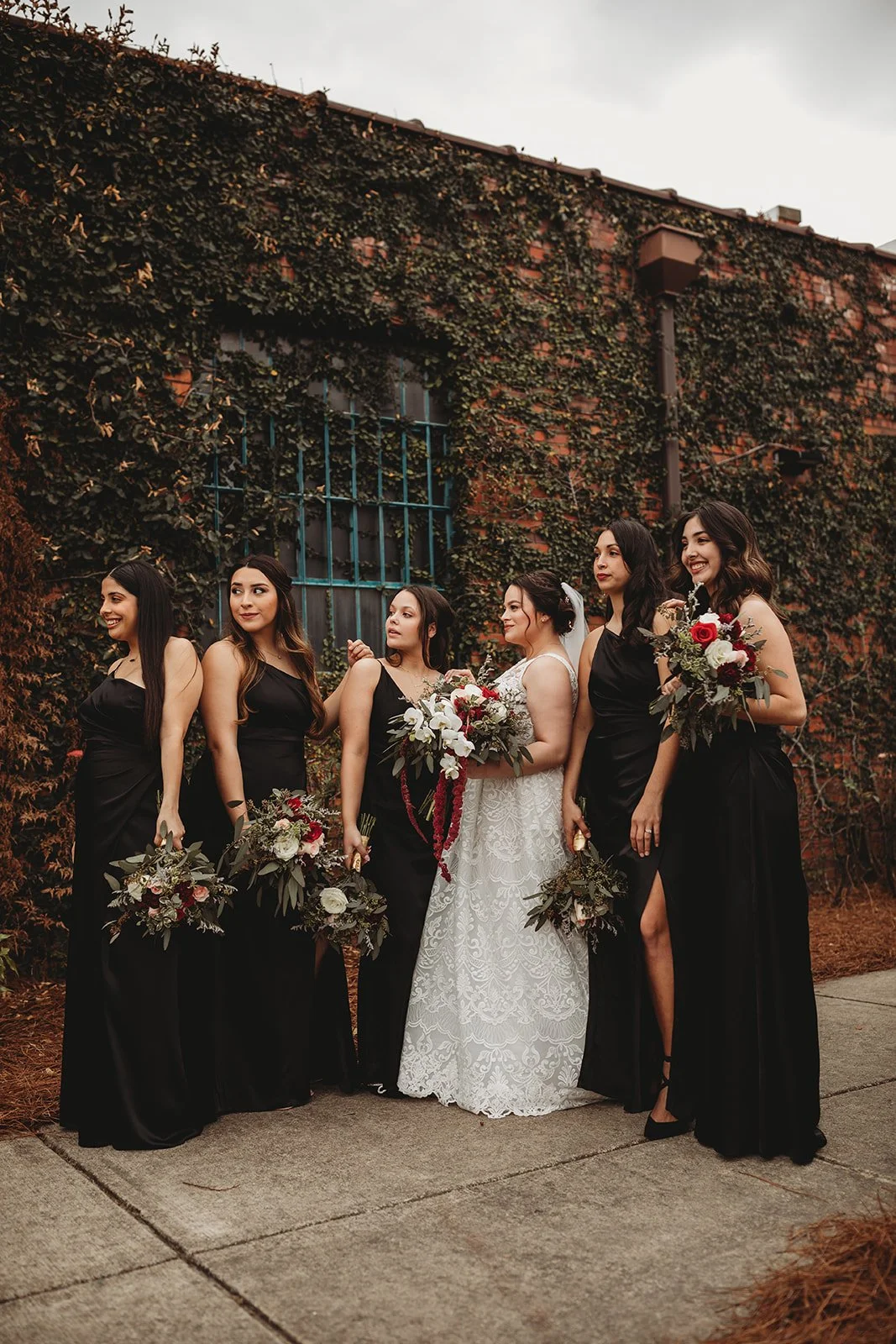 Bride and groom posing in front of the signature green ivy wall at Studio 215 in downtown Fayetteville, NC; a lush urban garden photography backdrop at our industrial warehouse venue near Fort Bragg and Raleigh.