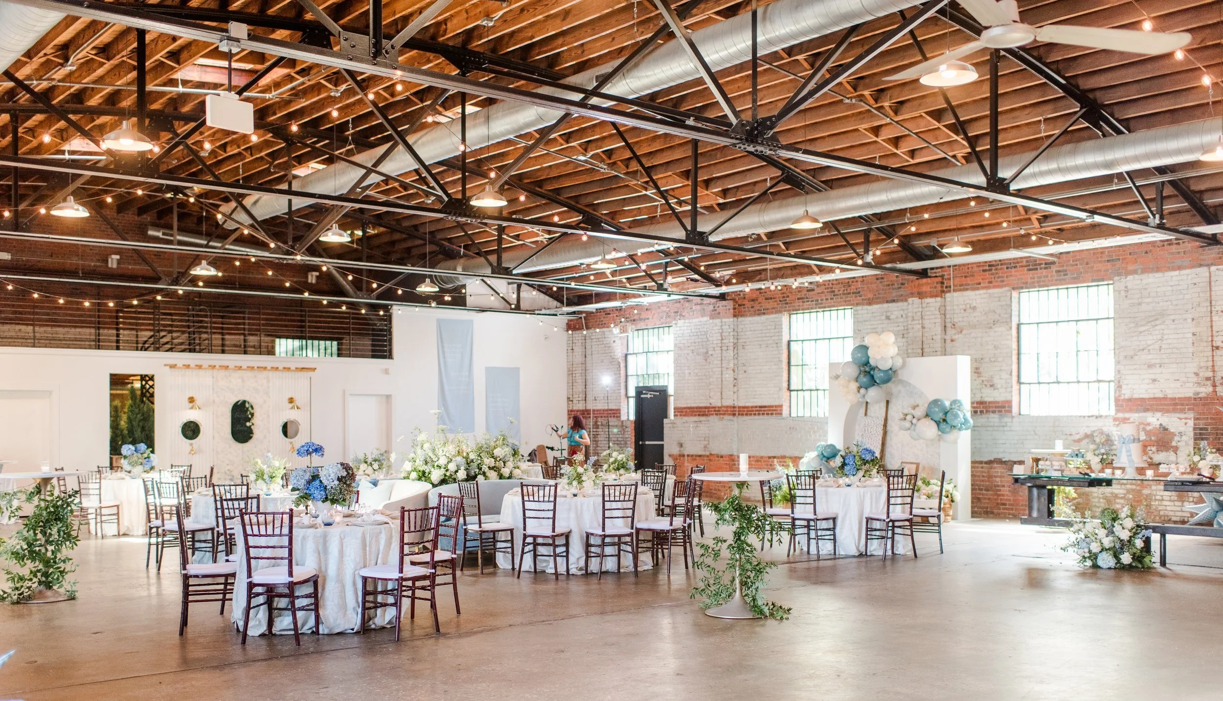 Industrial warehouse wedding venue at Studio 215 in Fayetteville, NC, located near Raleigh and Fort Bragg, featuring exposed brick, bistro lighting, and a modern chic aesthetic for weddings and events. 