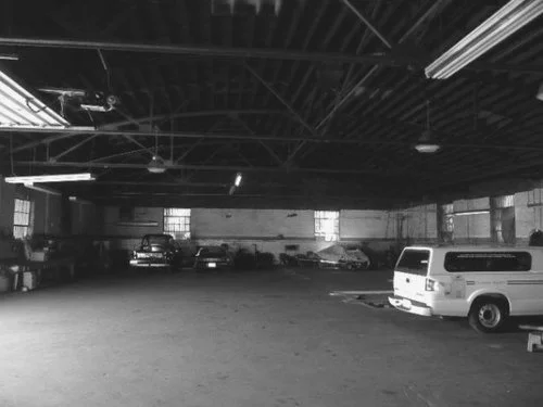 Empty indoor parking garage with parked cars on the sides.