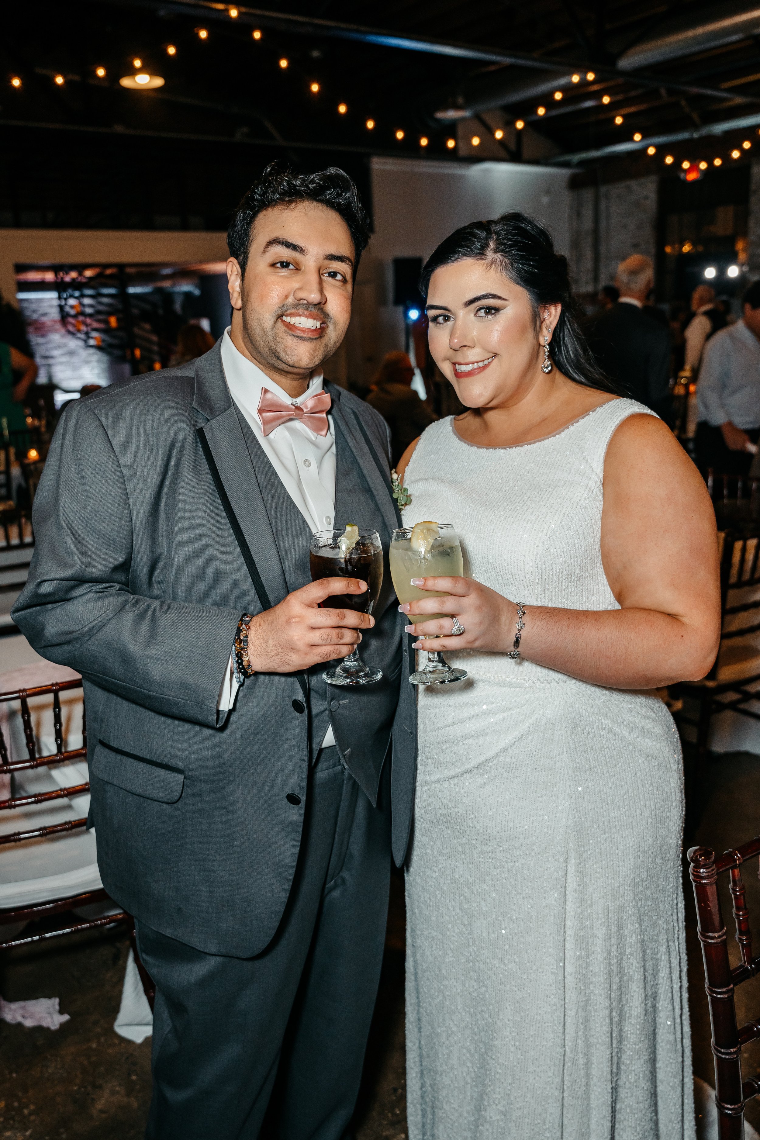 A man and woman dressed in formal attire holding drinks at a celebration or wedding reception.