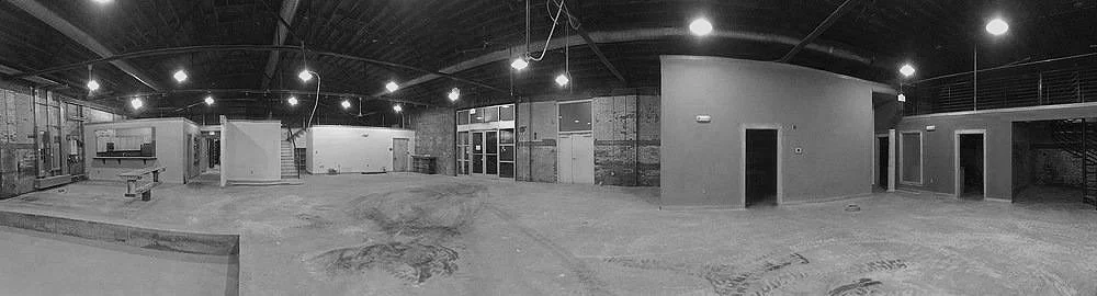 Empty construction site with unfinished building structure, exposed frameworks, and exposed wiring in black and white.