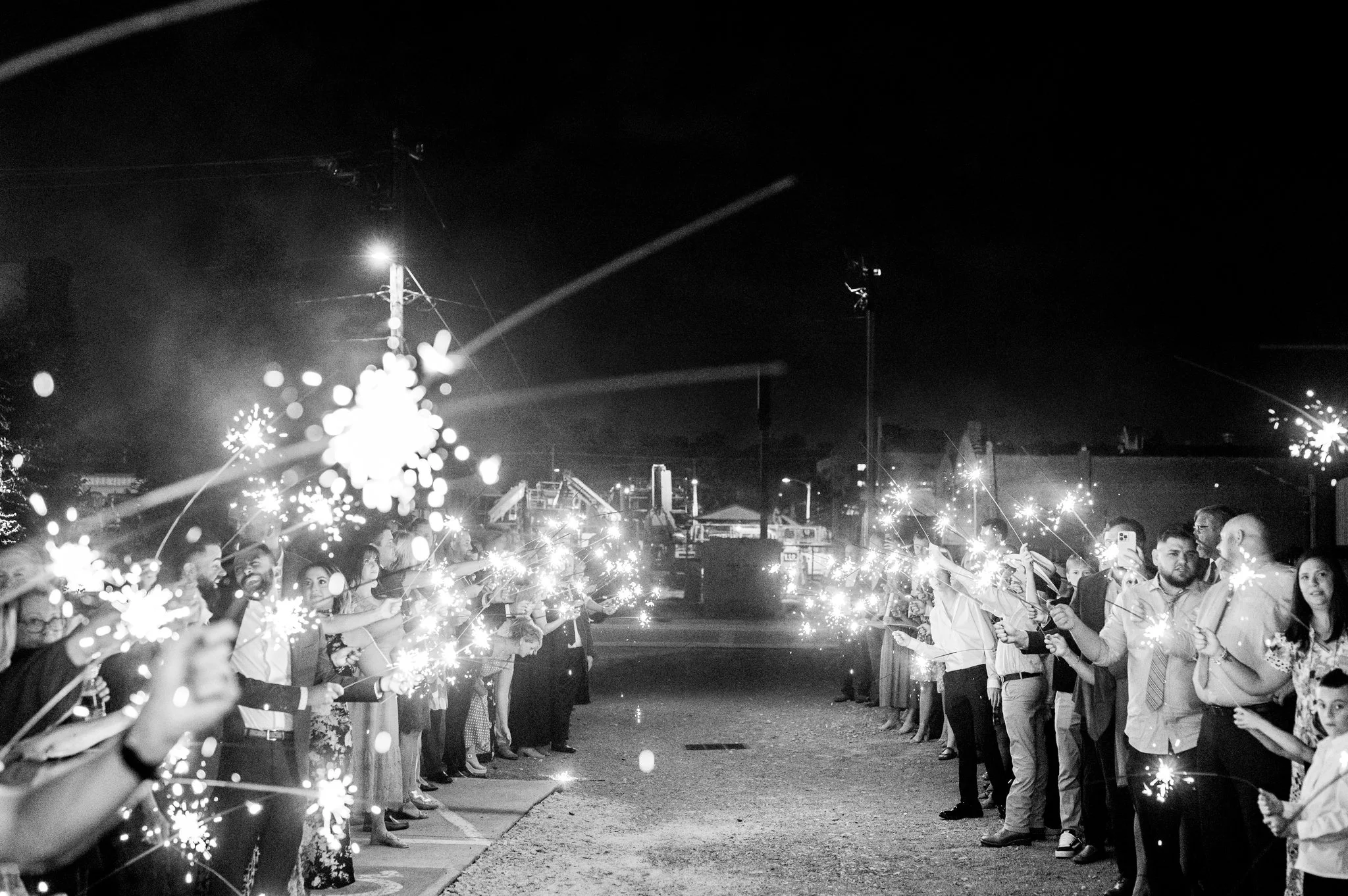 People standing in two lines at night holding sparklers during a celebration.