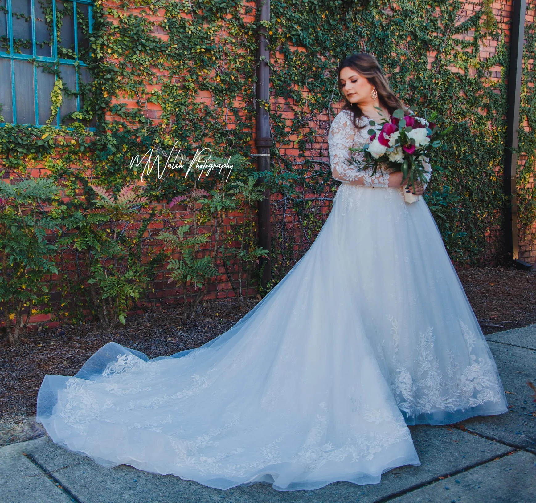 Bride and groom posing in front of the signature green ivy wall at Studio 215 in downtown Fayetteville, NC; a lush urban garden photography backdrop at our industrial warehouse venue near Fort Bragg and Raleigh.