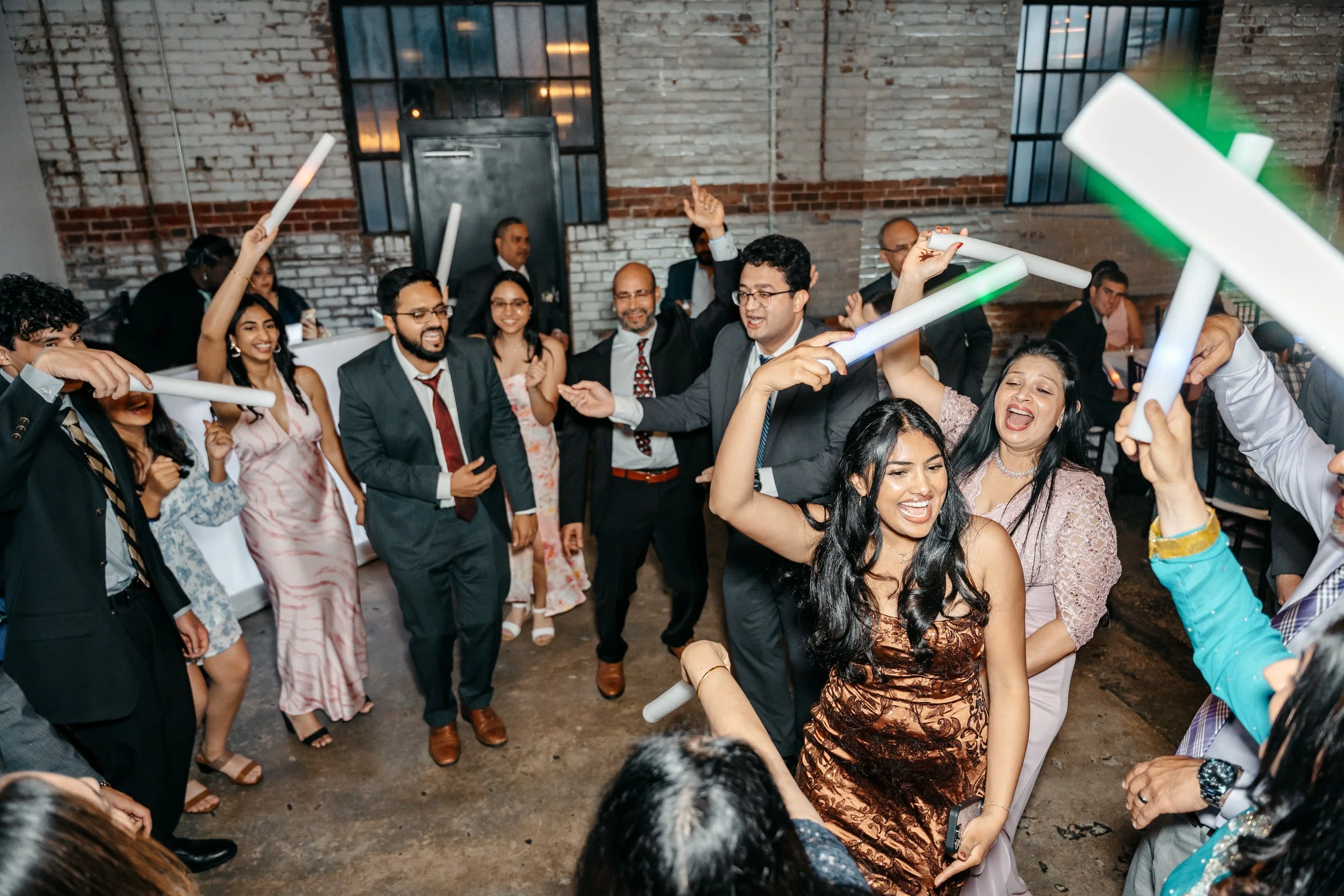 People dancing and celebrating at a party, holding glow sticks at Studio 215 a modern warehouse venue in Fayetteville, NC