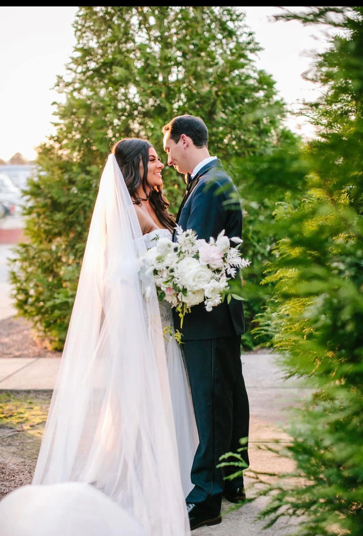 Bride and groom posing in front of the signature green ivy wall at Studio 215 in downtown Fayetteville, NC; a lush urban garden photography backdrop at our industrial warehouse venue near Fort Bragg and Raleigh.