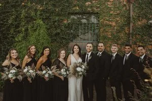 Bride and groom posing in front of the signature green ivy wall at Studio 215 in downtown Fayetteville, NC; a lush urban garden photography backdrop at our industrial warehouse venue near Fort Bragg and Raleigh.
