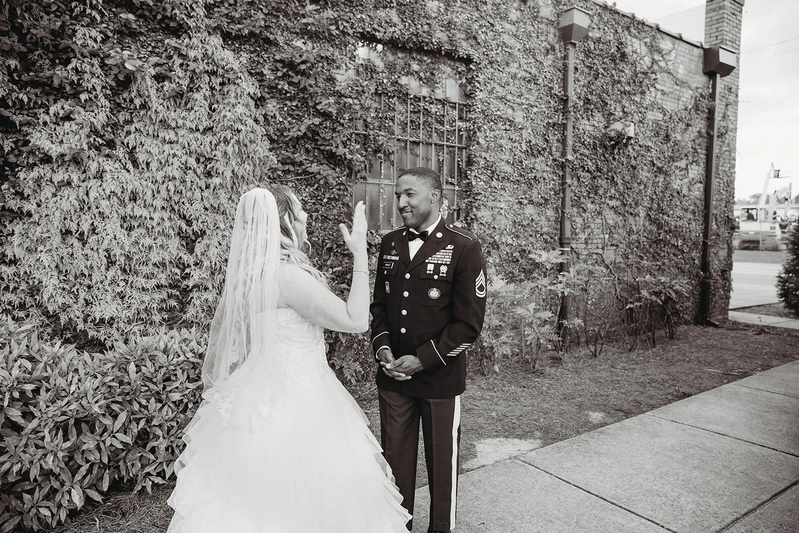 Bride and groom posing in front of the signature green ivy wall at Studio 215 in downtown Fayetteville, NC; a lush urban garden photography backdrop at our industrial warehouse venue near Fort Bragg and Raleigh.
