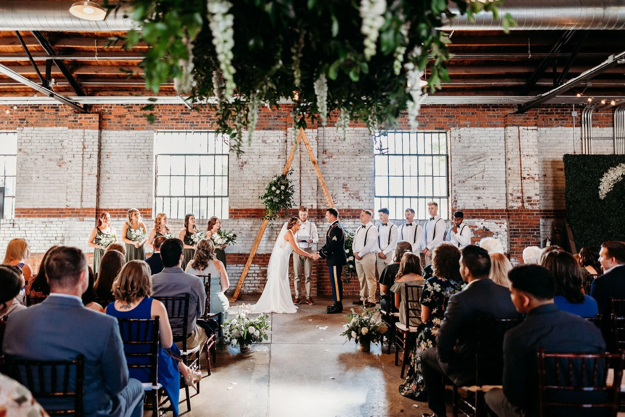 Industrial warehouse wedding venue at Studio 215 in Fayetteville, NC, located near Raleigh and Fort Bragg, featuring exposed brick, bistro lighting, and a modern chic aesthetic for weddings and events. 