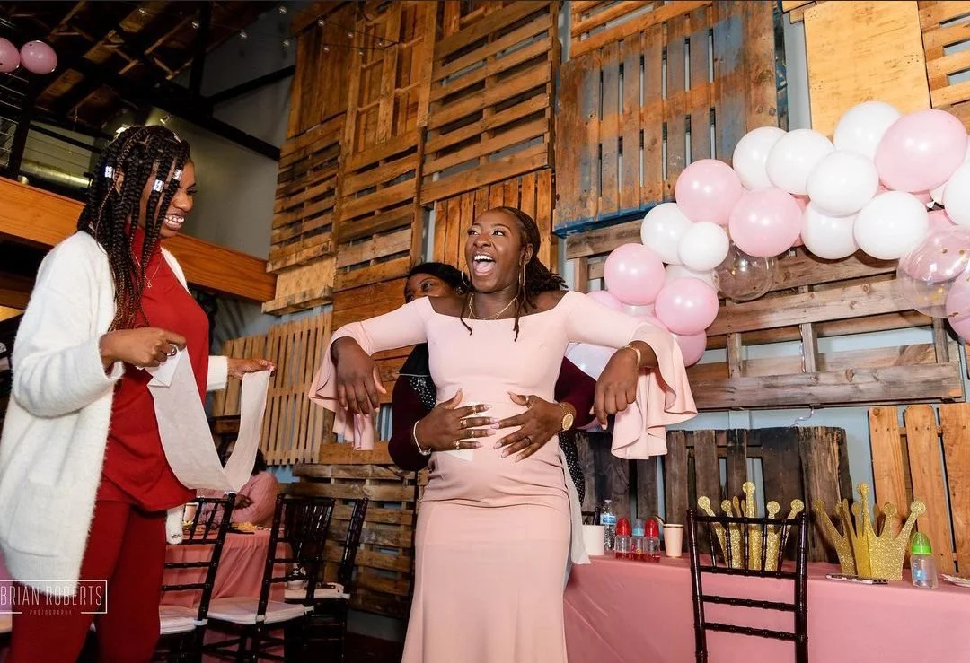 Elegant event setup at Little Studio 215 featuring a happy mom to be at her baby showerand a rustic wood pallet backdrop with pink balloon installations.