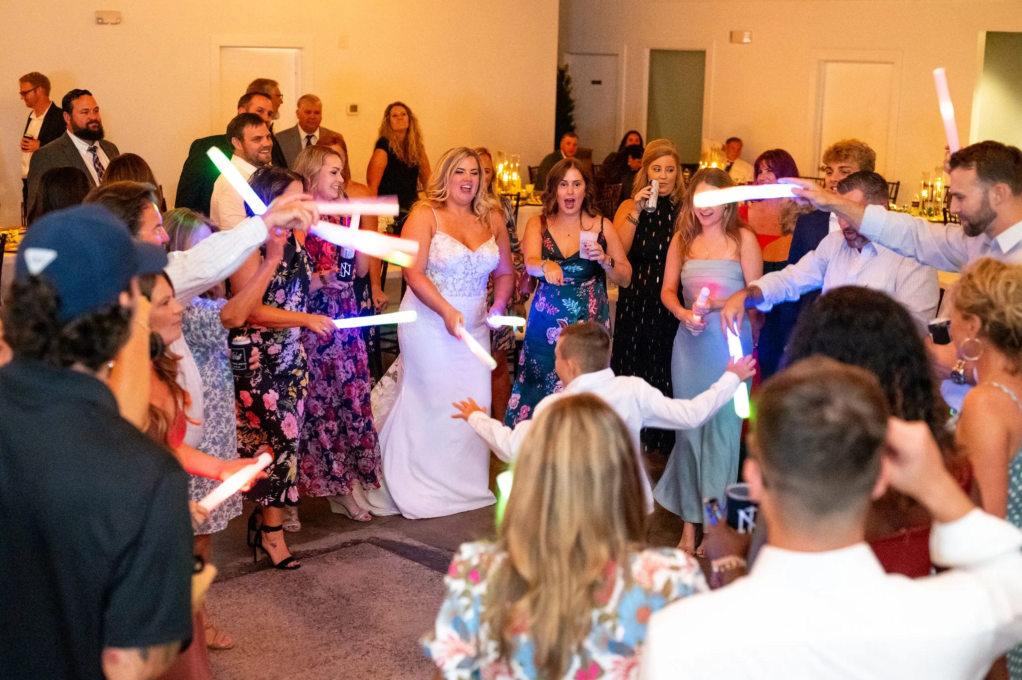 People dancing and celebrating at a wedding reception, holding glow sticks and enjoying the party at Studio 215 a modern warehouse venue in Fayetteville, NC