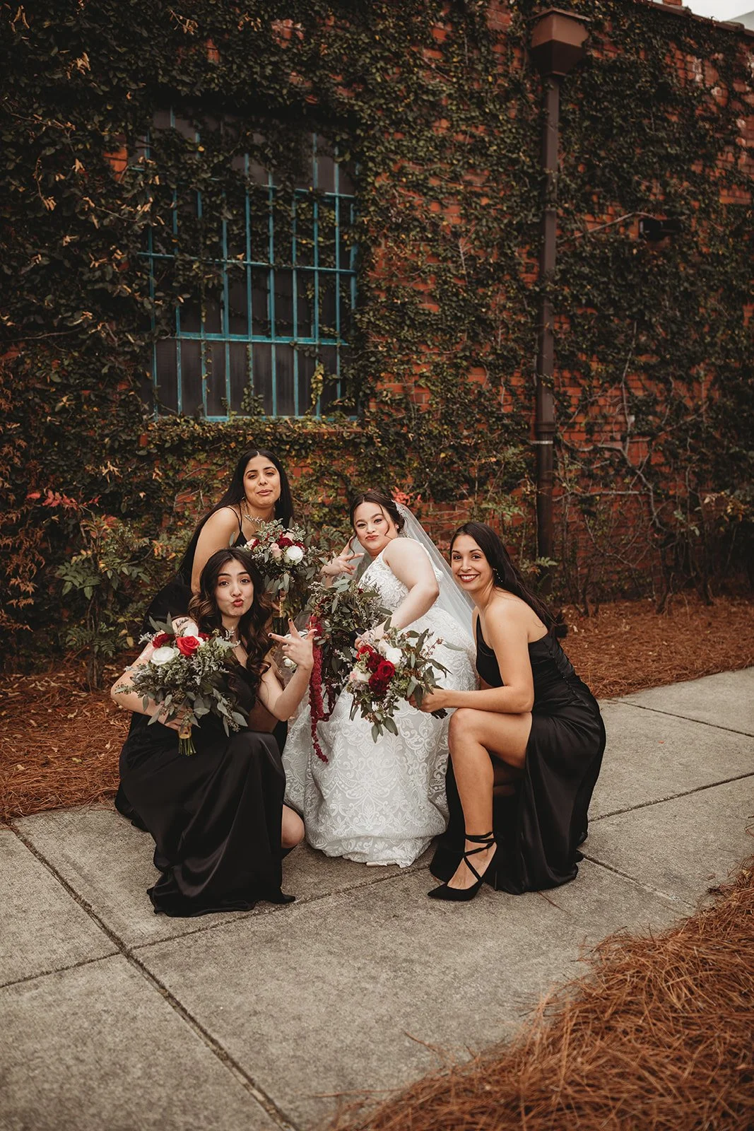 Bride and groom posing in front of the signature green ivy wall at Studio 215 in downtown Fayetteville, NC; a lush urban garden photography backdrop at our industrial warehouse venue near Fort Bragg and Raleigh.